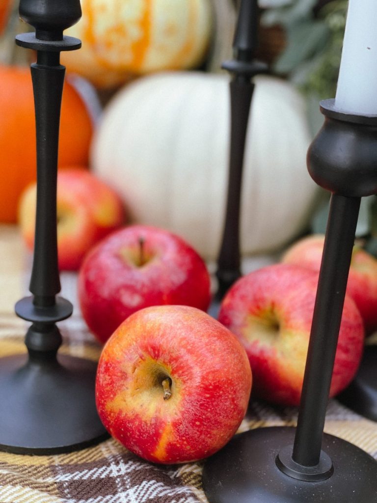 Create an outdoor tablescape with pumpkins, apples, candles and mums.