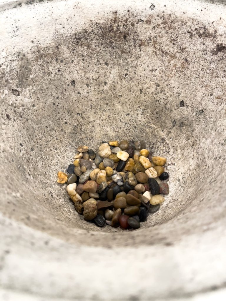 Adding gravel to a container to help with drainage.