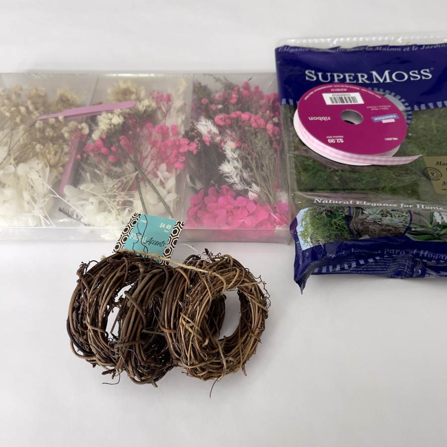 Supplies for creating mini spring wreaths with 3 inch grapevine wreaths, moss, dried flower assortment and pink and white gingham ribbon.