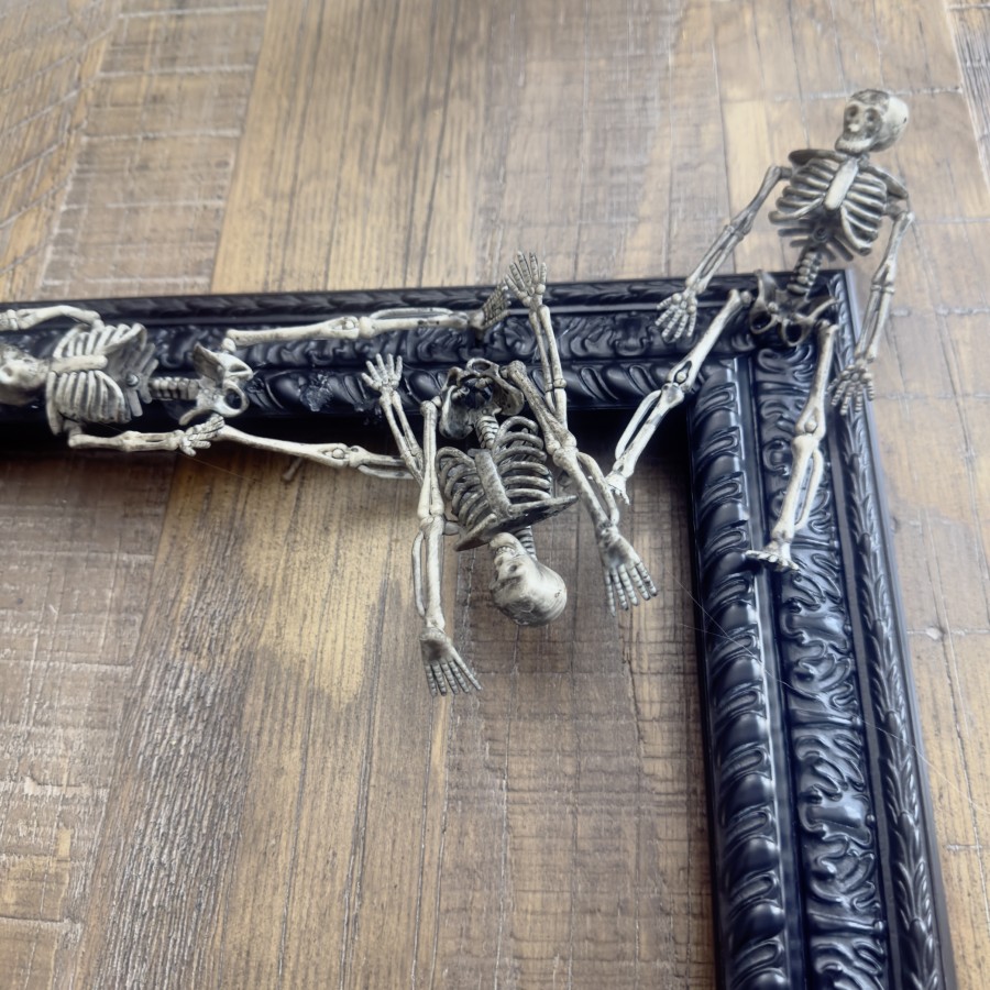 Skeletons glued to a frame for a spooky fun Halloween decor.