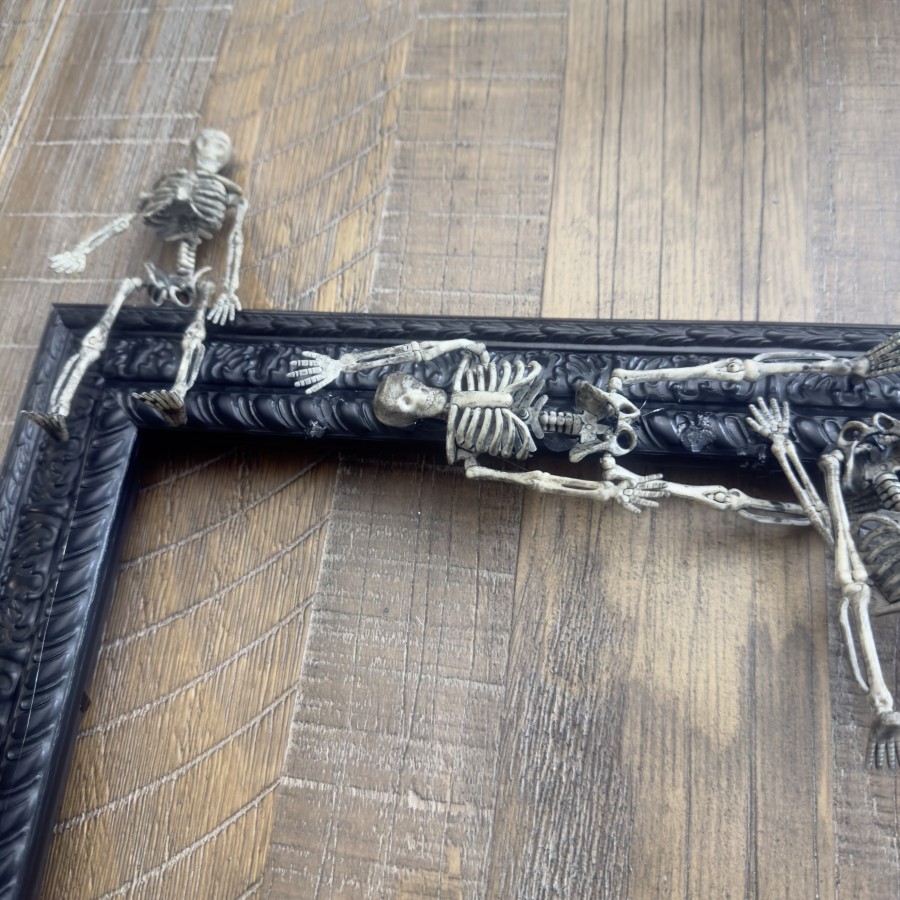 Skeletons in a variety of positions hot glued to a frame.